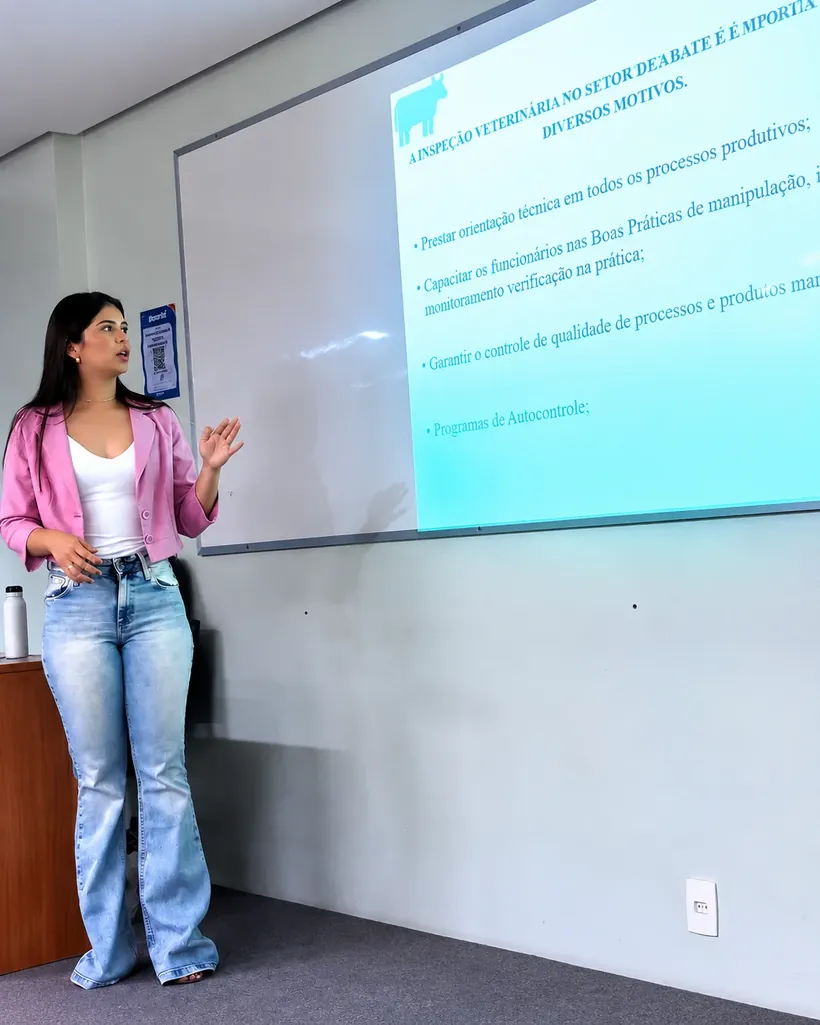 Consultora apresentando conteúdo técnico projetado em sala de capacitação